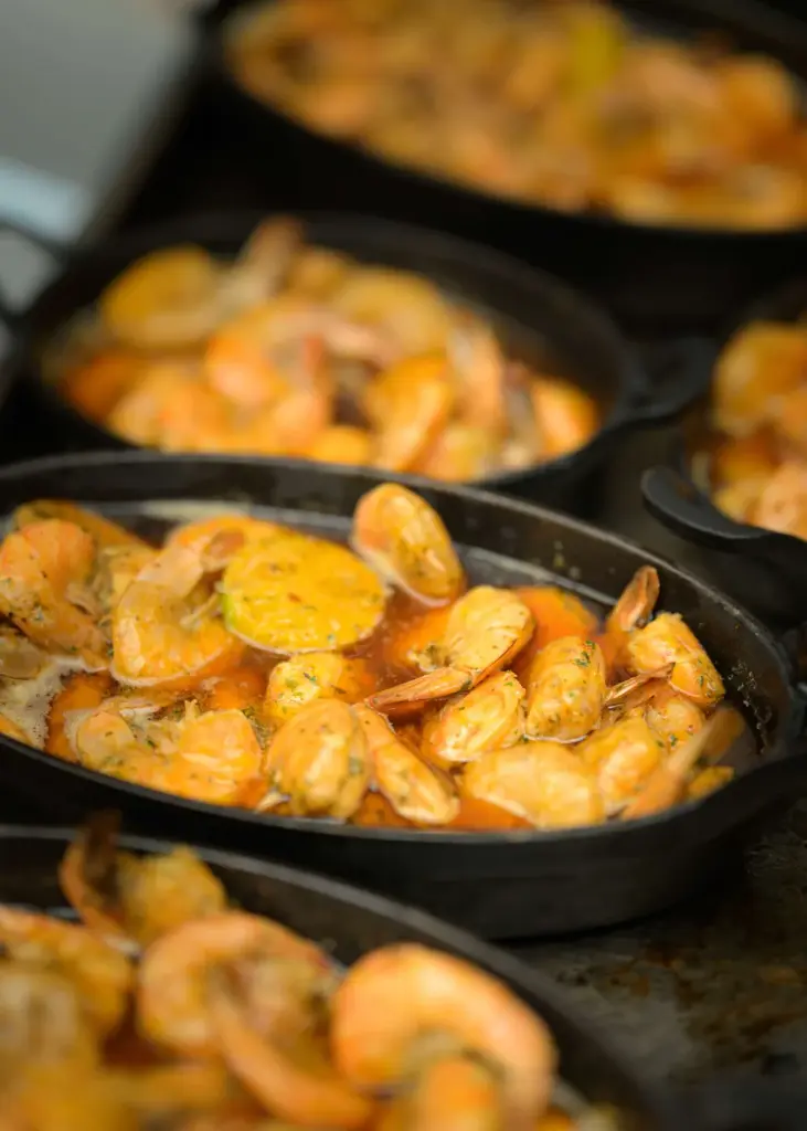 Gambas in gietijzeren pannen, vers bereid op locatie door de koks van La Casserole